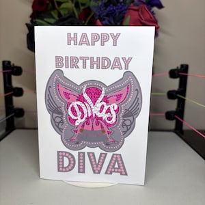 May include: A white birthday card with the words "HAPPY BIRTHDAY DIVA" in pink and gray lettering. The card features a pink and gray graphic design with a decorative pattern.