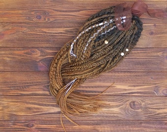 May include: A close-up of a brown and blonde hair extension with white string accents. The hair extension is lying on a wooden surface.