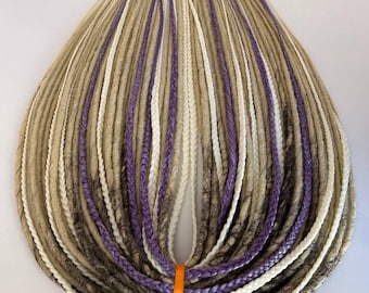 May include: A set of synthetic dreadlocks in shades of beige, white, and purple, tied together with an orange ribbon. The dreads are arranged in a symmetrical pattern, showcasing the various colors and textures.