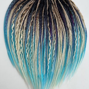 May include: A set of synthetic dreadlocks in various shades of blue, white, and black. The dreadlocks are arranged in a heart shape and have a ombre effect, transitioning from dark to light.
