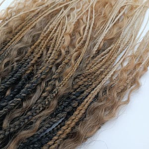 Puede incluir: Primer plano de extensiones de cabello sintético en varios tonos de marrón y negro. Las extensiones incluyen trenzas y mechones ondulados, con un efecto degradado.