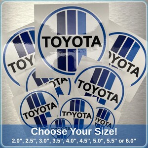 May include: A selection of white and blue Toyota logo stickers in different sizes. Each sticker displays the Toyota name in black, inside a white circle with blue stripes. The text "Choose Your Size!" is at the bottom, with sizes from 5.08 cm to 15.24 cm.