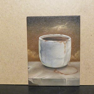 May include: An oil painting on canvas depicting a white ceramic cup filled with dark liquid. The cup sits on a light-colored stone surface with a brown circular stain. The background is a gradient of dark brown and gold tones with textured brushstrokes.
