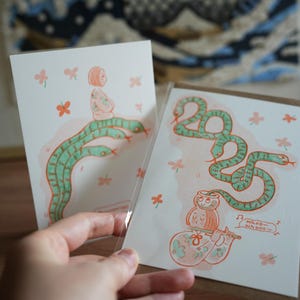 Tarjetas de felicitación del Año Nuevo chino 2025 con una encantadora serpiente: regalo de acuarela con el zodíaco chino impreso en Riso para el Año Nuevo lunar
