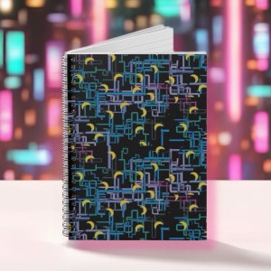 Può includere: Un quaderno a spirale nero con un motivo geometrico colorato con lune crescenti gialle. Il motivo è composto da linee blu, verdi, viola e rosa.