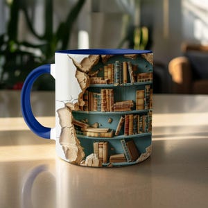 Könnte beinhalten: Eine weiße Keramik-Tasse mit blauem Innenraum und Henkel. Die Tasse zeigt ein einzigartiges Design einer Bücherregal-Szene, die durch eine Wand bricht. Das Bücherregal ist mit Vintage-Büchern in verschiedenen Größen und Farben gefüllt.