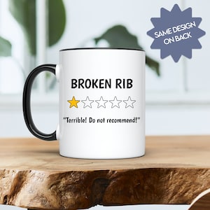 May include: White coffee mug with a black rim and handle. The mug has a black and white graphic of a one-star rating with the text "BROKEN RIB" and "Terrible! Do not recommend!"