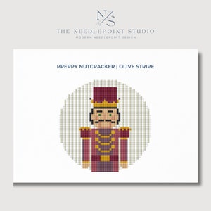 Puede incluir: Un patrón de punto de aguja de un cascanueces elegante con un uniforme rojo y dorado sobre un fondo de rayas oliva. El patrón se titula "Preppy Nutcracker | Olive Stripe".