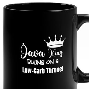 Op de afbeelding: Zwarte koffiemok met witte tekst die "Java King Ruling on a Low-Carb Throne!" luidt en een kroonafbeelding.