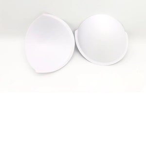 Könnte beinhalten: Zwei weiße BH-Cups aus Schaumstoff, um einem BH mehr Volumen zu verleihen.