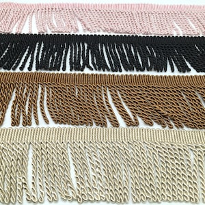 May include: Four different colours of twisted fringe trim. The colours are pink, black, brown, and beige.