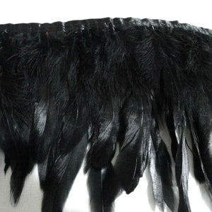 May include: Black feather trim with a satin backing. The feathers are soft and fluffy, and the trim is perfect for adding a touch of elegance to any project.