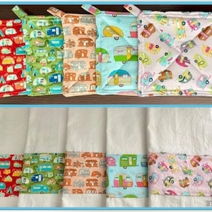 May include: Set of six colorful kitchen towels with a border of a repeating pattern of vintage camper vans. The towels are white with a band of color at the bottom.
