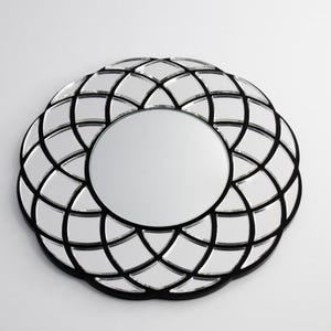 May include: A round, black framed mirror with a geometric design. The mirror has a silver finish and a black frame.