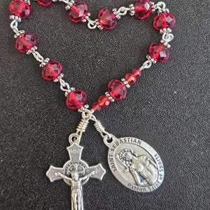 TR037- Handmade tenner decade pocket rosary.  Ruby red colored facetted glass beaded chaplet. St. Sebastian. St Benedict cross.