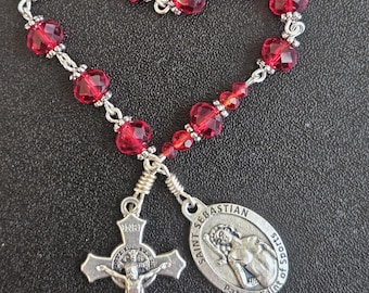 TR037- Handmade tenner decade pocket rosary.  Ruby red colored facetted glass beaded chaplet. St. Sebastian. St Benedict cross.