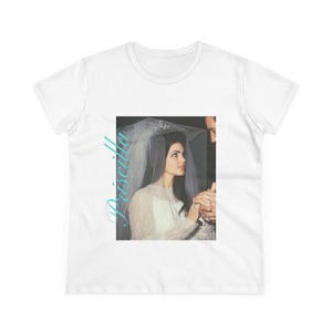 Pode incluir: Uma camiseta branca com uma foto em preto e branco de uma noiva e um noivo. A noiva está usando um véu e um vestido brancos. O noivo está usando um terno escuro. O texto "Priscilla" está escrito em azul no lado esquerdo da imagem.