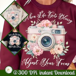 May include: Burgundy sweatshirt featuring a camera design with floral accents and the text "When Life Gets Blurry, Adjust Your Focus." The design is also shown on a beige and black t-shirt. The image includes the text "300 DPI instant Download."