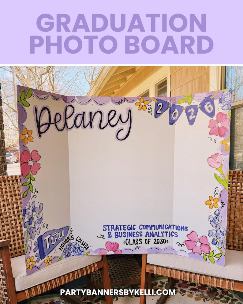May include: A tri-fold white display board featuring hand-painted floral borders in pink, yellow, and purple. The board displays the name Delaney, the year 2026 on a banner, and text reading TCU Honor's College and Strategic Communications & Business Analytics Class of 2030.