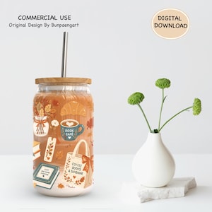 May include: A clear glass tumbler with a wooden lid and metal straw, featuring a printed design of autumn leaves, a croissant, a coffee mug labeled Book Cafe, a bookmark, a book labeled Just One More Chapter, and a tote bag labeled Coffee Books & Sunshine.