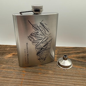 Könnte beinhalten: Eine Edelstahl-Flachmann mit einer schwarzen Grafik einer Berg-Skikarte und dem Text "Mammoth Mountain". Ein kleiner silberner Trichter befindet sich neben der Flasche. Die Flasche hat einen Schraubverschluss und einen Klappdeckel.
