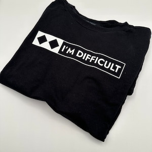 May include: Black t-shirt with a white graphic of two diamonds and the text "I'M DIFFICULT".