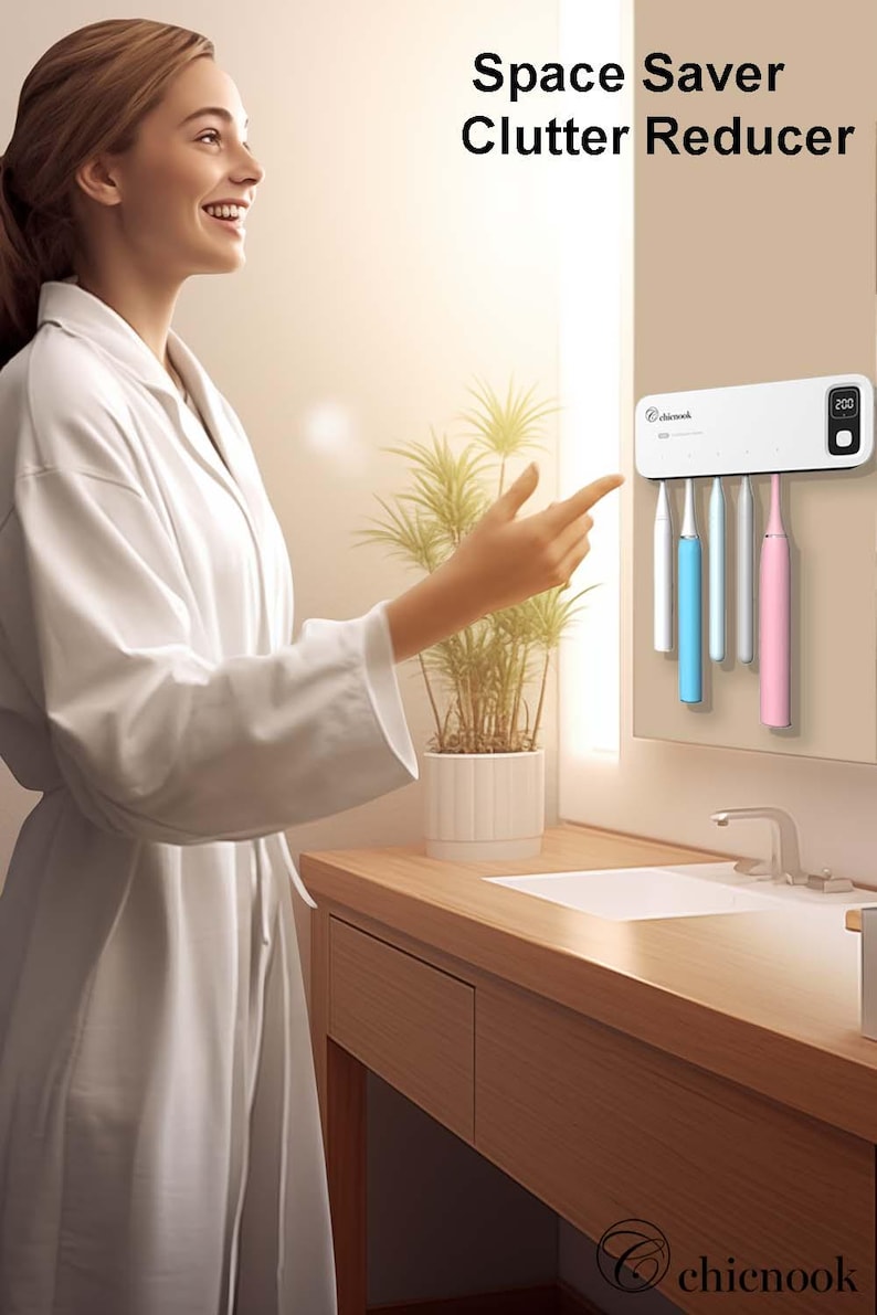 Puede incluir: Un soporte blanco para cepillos de dientes con el texto "Space Saver Clutter Reducer" y una pantalla digital. El soporte tiene ranuras para cepillos de dientes en azul, blanco y rosa. El producto est&aacute; montado en una pared en un ba&ntilde;o.