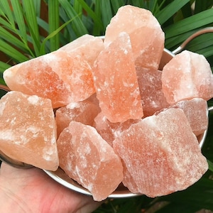 Puede incluir: Un bol de grandes cristales de sal rosa del Himalaya, rugosos. Los cristales de sal son de diversas formas y tamaños.