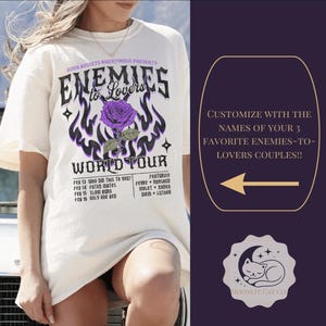 May include: Off-white t-shirt with a graphic design featuring a purple rose, flames, and the text "Enemies to Lovers World Tour." The shirt also includes a list of dates and names. The design is in black and purple.