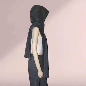 May include: A charcoal gray hooded scarf with a long, flowing design. The scarf is made of a soft, comfortable fabric and can be worn in a variety of ways.