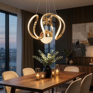 May include: A gold-toned pendant light fixture featuring three curved, illuminated arms and a central spherical light element with a textured, frosted glass base, suspended from a circular ceiling canopy by thin, metallic wires.