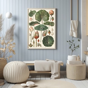 May include: Botanical print featuring detailed illustrations of lotus flowers and leaves in various stages of growth. The artwork showcases a beige background with green and peach-colored botanical elements, framed in a light wood frame. The print is displayed in a room with light blue walls.