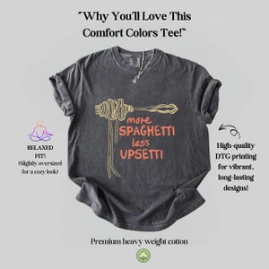 May include: A dark gray t-shirt with a relaxed fit featuring a graphic of a fork and spaghetti with the text "more spaghetti less upsetti". The shirt is made of premium heavy weight cotton and features high-quality DTG printing for vibrant, long-lasting designs.