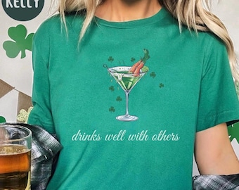 May include: Green t-shirt with a green martini glass with two carrot sticks in it. The text "drinks well with others" is printed below the glass.