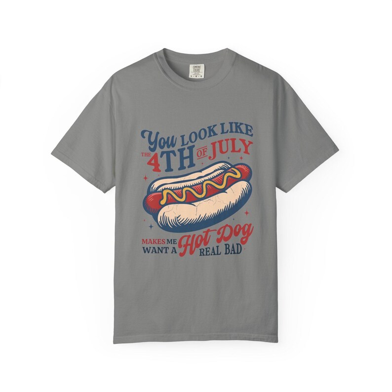 K&ouml;nnte beinhalten: Graues T-Shirt mit einer Abbildung eines Hotdogs und dem Text "You look like the 4th of July, makes me want a hot dog real bad." Der Hotdog ist rot, gelb und wei&szlig;.