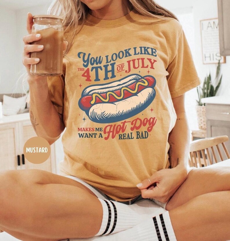 K&ouml;nnte beinhalten: Senffarbenes T-Shirt mit einem Hotdog-Motiv und dem Text "You look like the 4th of July makes me want a hot dog real bad." Das T-Shirt hat einen l&auml;ssigen Stil.