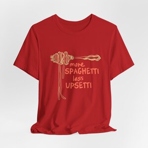 May include: Red t-shirt with a graphic of a fork with spaghetti on it and the text "more spaghetti less upsetti".