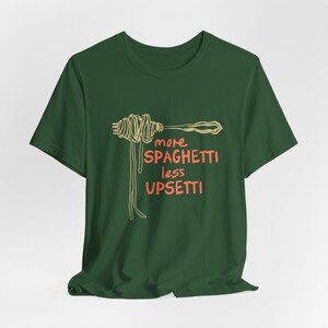 May include: A green t-shirt with a graphic of spaghetti on a fork and the text "more spaghetti less upsetti" in orange.