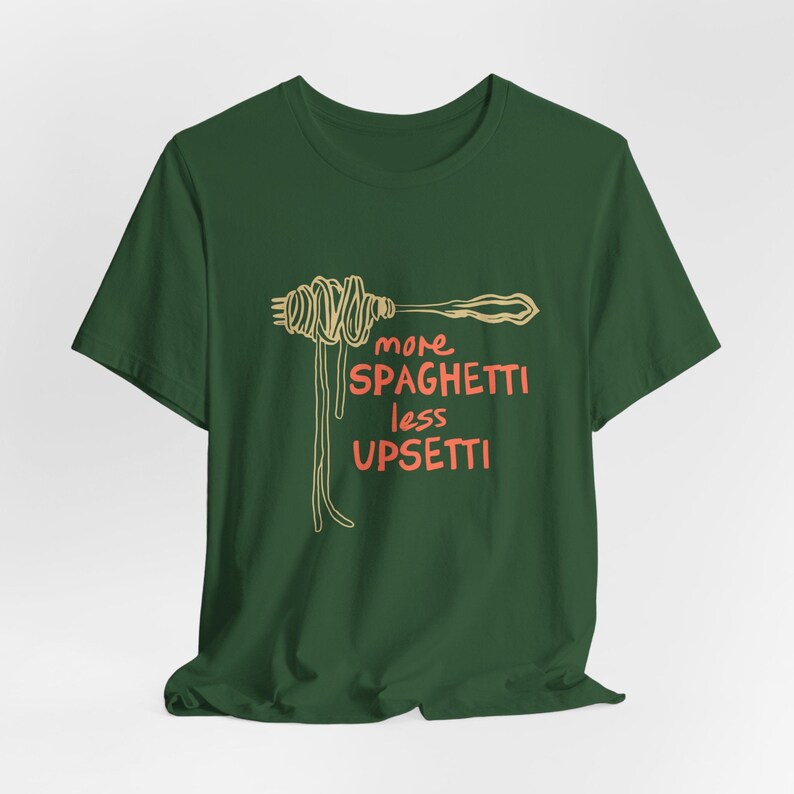 May include: A green t-shirt with a graphic of spaghetti on a fork and the text "more spaghetti less upsetti" in orange.