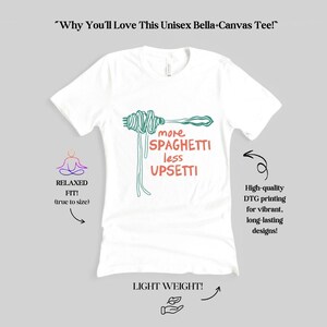 May include: White unisex t-shirt with a green and orange graphic of a fork with spaghetti on it. The text "more spaghetti less upsetti" is printed on the shirt.