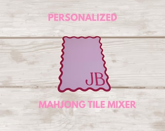 May include: A rectangular, light purple mahjong tile mixer with a scalloped edge and a dark pink border. The letters JB are printed in dark pink on the lower right side. The text PERSONALIZED and MAHJONG TILE MIXER appear in pink.