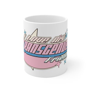 Puede incluir: Taza de cerámica blanca con un diseño rosa y azul que dice "Amo a mis amigos transgénero".