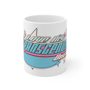 May include: White ceramic mug with a blue, pink and yellow graphic that says "I love my transgender vibe".