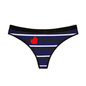Puede incluir: Tanga de color azul y blanco a rayas con un corazón rojo en la parte delantera.