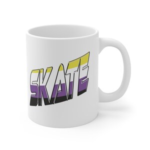 Może przedstawiać: Biały ceramiczny kubek z napisem "SKATE" w kolorach flagi dumy osób niebinarnych. Tekst jest pogrubiony, w stylizowanej czcionce z czarnym obrysem. Kubek ma zakrzywiony uchwyt.