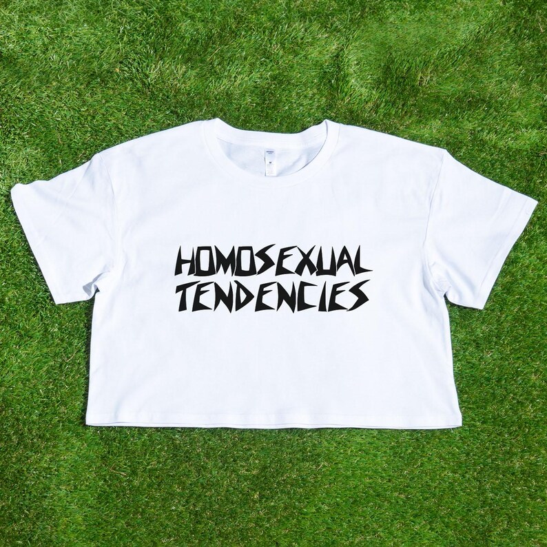 May include: White crop top with black text that reads "HOMOSEXUAL TENDENCIES".