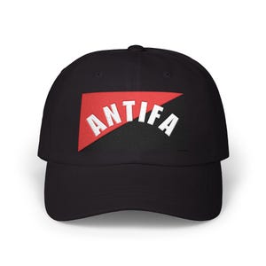 May include: Black baseball cap with a red triangle patch. The patch features the white word "ANTIFA" in a curved, bold font. The cap has a curved brim and a structured crown.