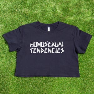 May include: A black cropped t-shirt with the text "HOMOSEXUAL TENDENCIES" printed in white.