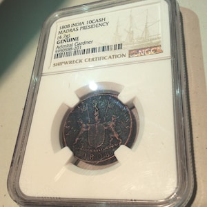 May include: A copper 1808 India 10 Cash coin from the Madras Presidency, certified as genuine. The coin, weighing 4.7g, is encased in a protective holder with the text "SHIPWRECK CERTIFICATION" and "Admiral Gardner".