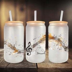 May include: Three frosted glass tumblers with bamboo lids and clear straws. Each tumbler features a black and white musical note design with gold accents. The middle tumbler has the name "Hannah" printed on it.